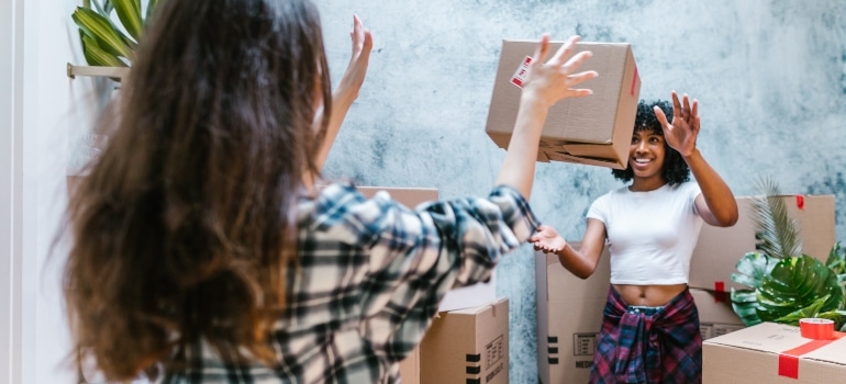 two girls throwing boxes to each other