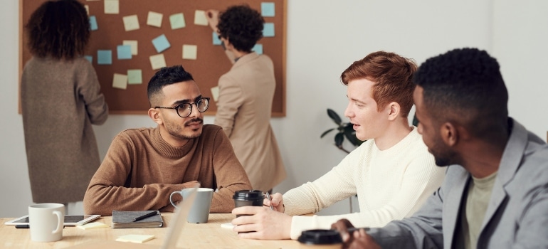 employees talking in the office as an example of what you should do when moving your business to a new location